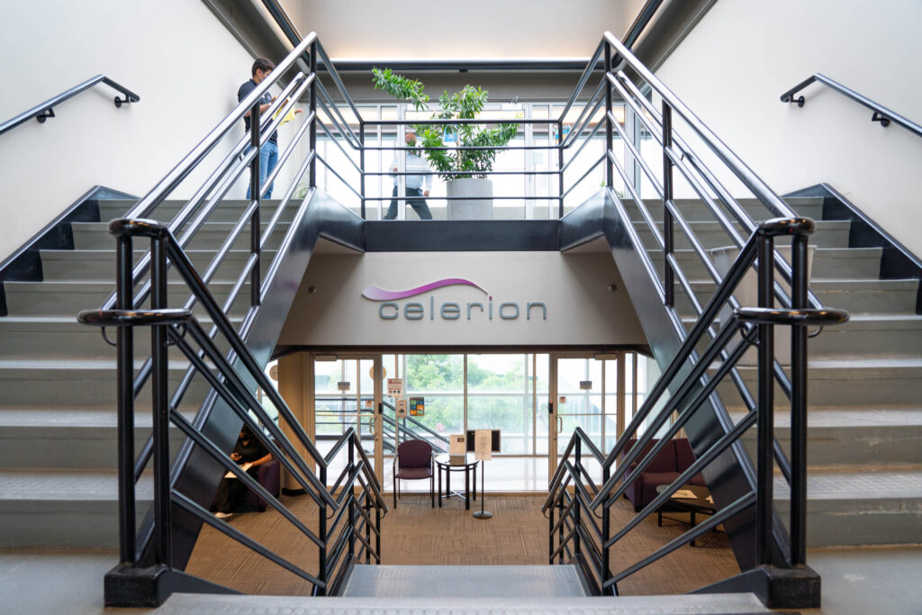 Two staircases frame the Celerion logo on a wall of an office building.