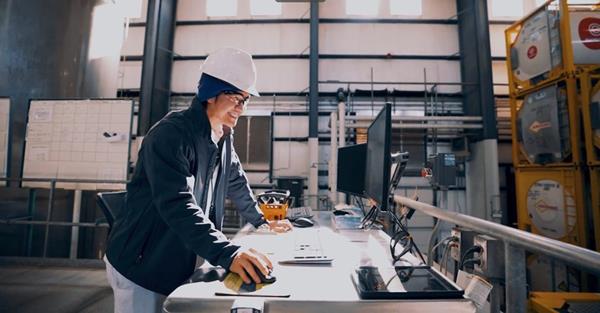 A student in a hardhat works in an industrial area. 