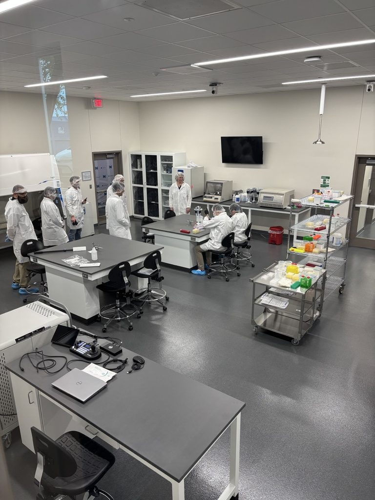 A lab space with several people in white coats and hairnets.