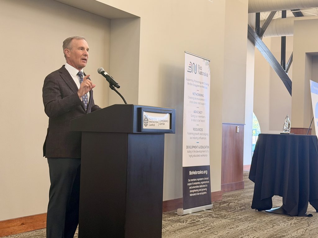 Bio Nebraska Executive Director presents this year's 2026 Governor's Bioscience Award. He stands at a podium.